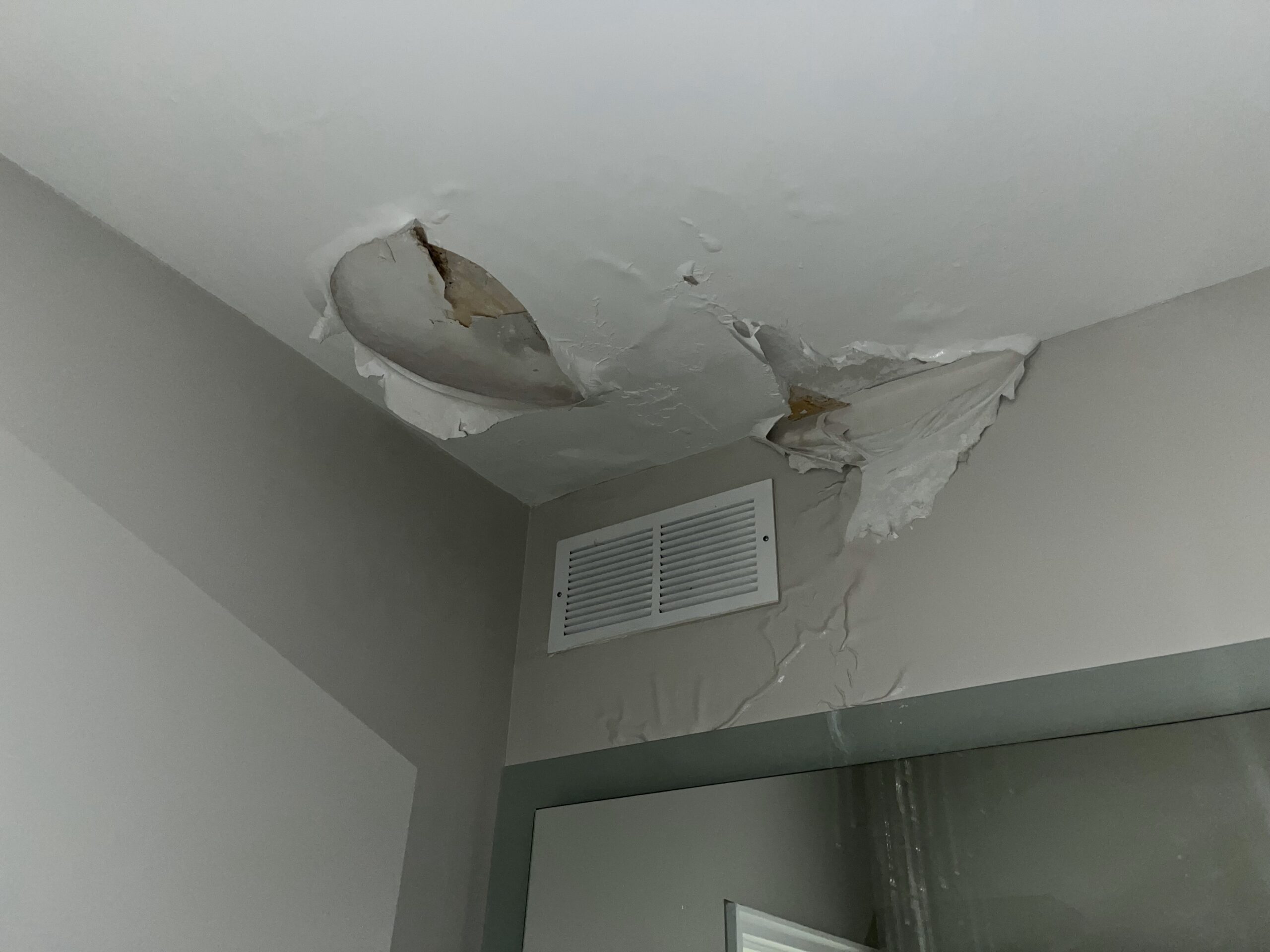 Photo of water leaking through the ceiling of an apartment unit.